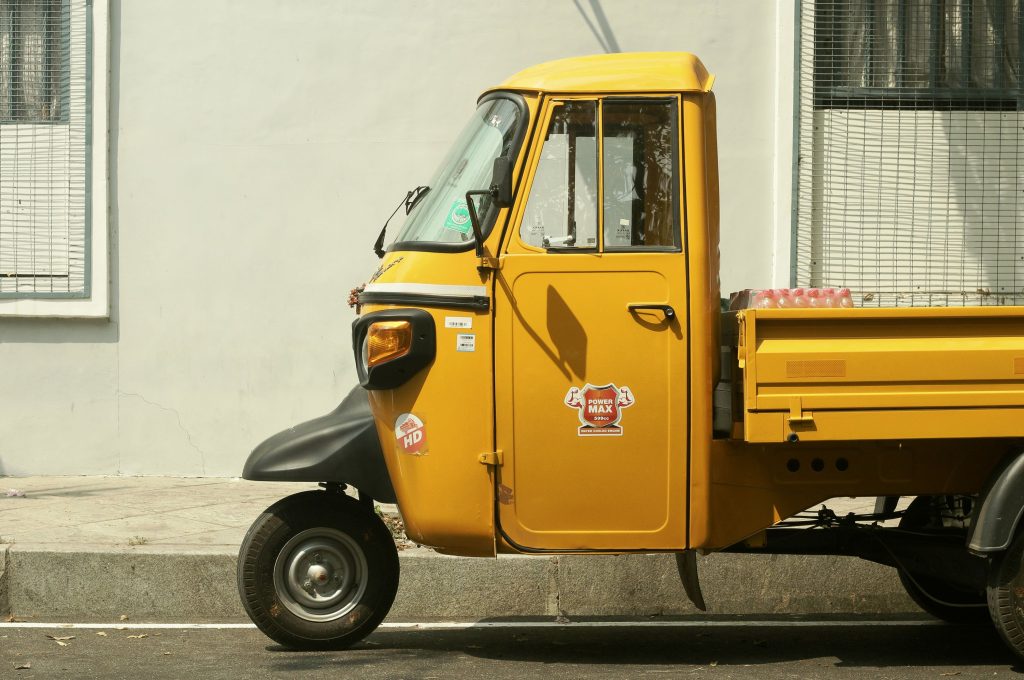 Close-up of a yellow Piaggio Ape three-wheeler parked on a street in Puducherry, India.